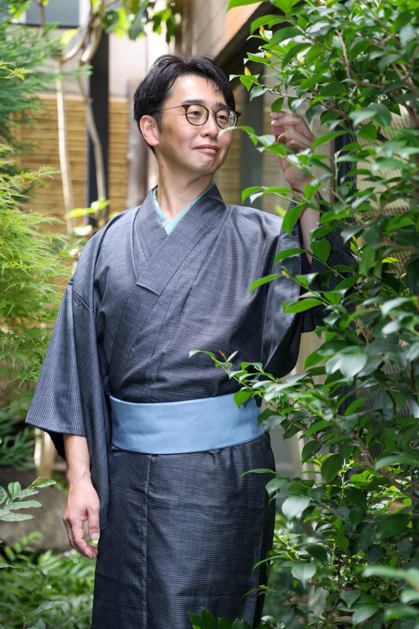 木々のそばで着物を着た三田村利さんの写真。